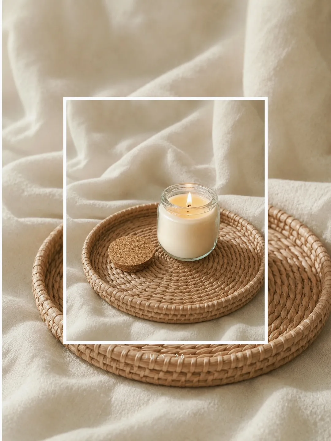 A hand-poured Snug Scents glass jar candle glowing softly on a woven rattan tray