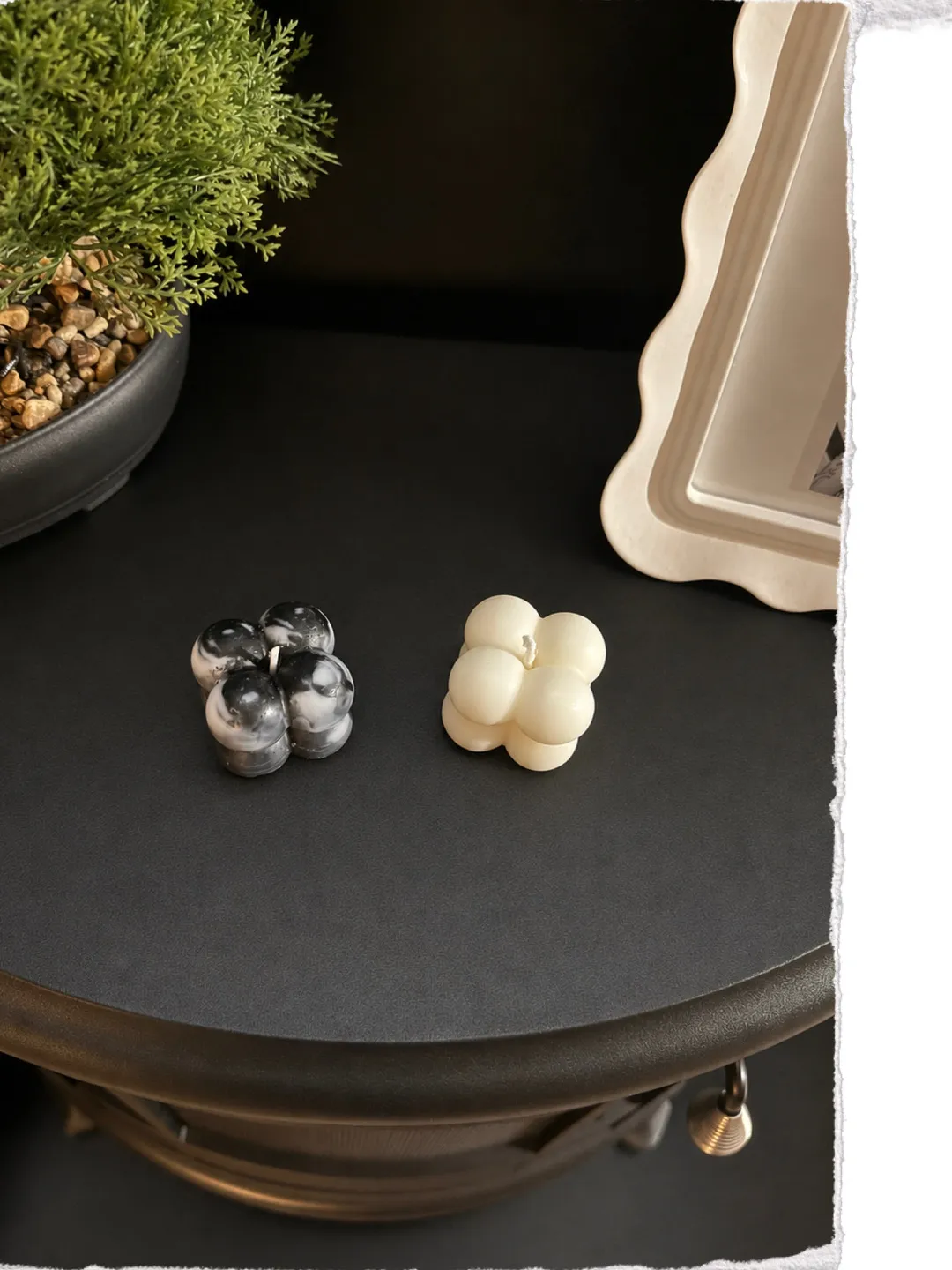 Cream and marbled black bubble candles styled on a dark side table